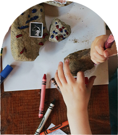 4 child's hands playing with crayons and rocks